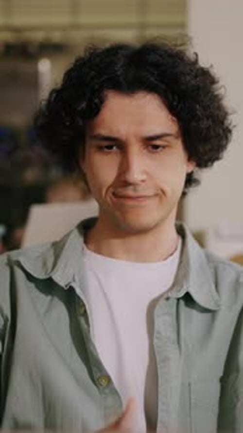 Curly Haired Young Man Concentrating on Laptop Work at Home Office Desk Focused Expression While