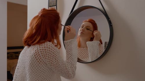 Young woman applies eye makeup in natural morning routine at home