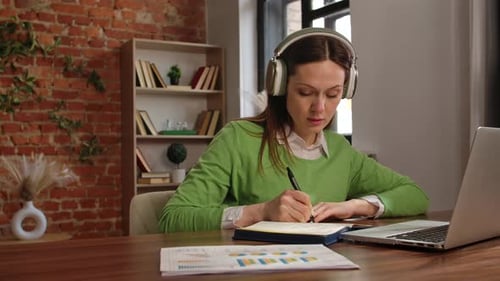 Woman Engaged in Remote Work Wearing Headphones in Modern Office