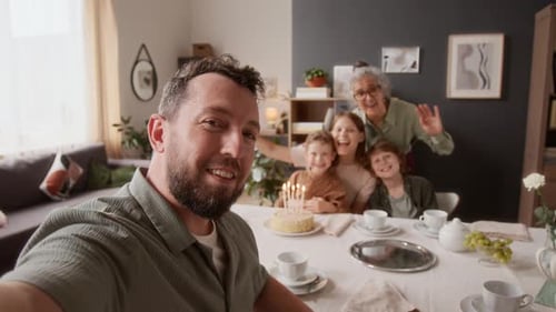 POV de um homem gravando um vídeo de uma família extensa acenando alegremente para a câmera
