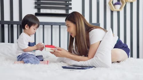 Mom Giving Birthday Gift to Child on Bed