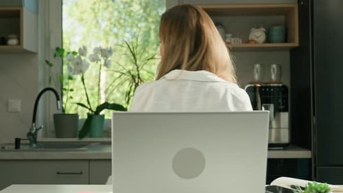 Woman Working on Laptop in Bright Kitchen