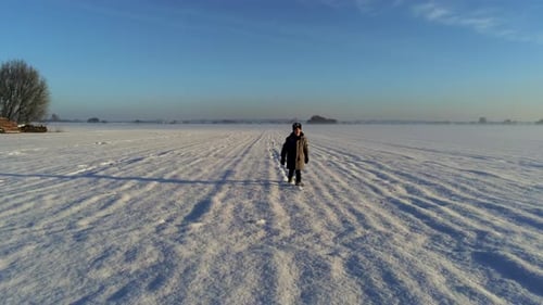 Dolly shot of little boy walking on field full of snow