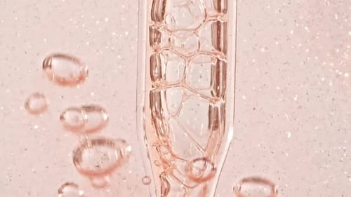 Gel liquide cosmétique transparent avec bulles moléculaires et huile s'écoulant dans un tube en verre avec liquide transparent