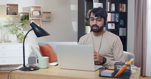 Arabian Young Man in Headset Working at Computer and Videochatting at Home Call Center Worker at