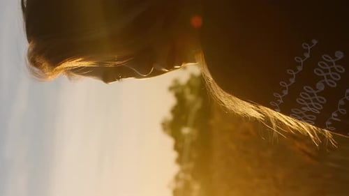 Vertical beautiful romantic village girl with long blond hair watching on sunset or sunrise rays