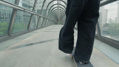 Skateboarder Riding Inside a Modern Glass Pedestrian Bridge