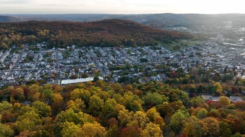 Urban American city with colorful mountain foliage in USA. Aerial at golden hour.