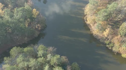 Aerial of lake surrounded by forest, revealing hiking path