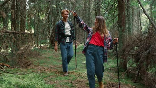 Smiling Tourists Hiking In Fairytale Forest. Positive Girl And Guy Walking Between Green Trees In...