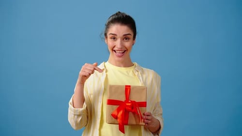 Smiling Brunette Woman Offering a Wrapped Gift