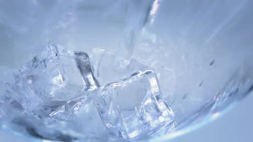 Ice Cubes and Water Filling Glass