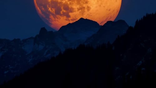 Giant Orange Moon Rises Over Dark Mountain Landscape