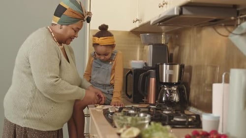 Grandmother Cooking Food for Lunch for Granddaughter