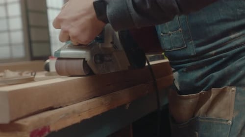Carpenter Using Belt Sander in Workshop