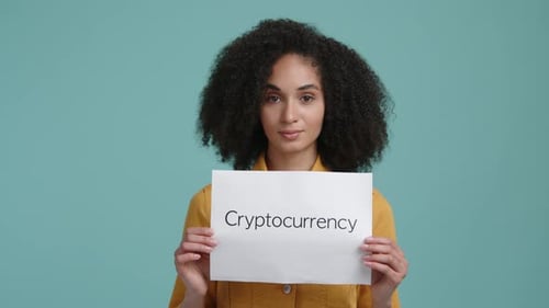 Femme brune en vêtements décontractés tenant un livre blanc avec un mot cryptomonnaie