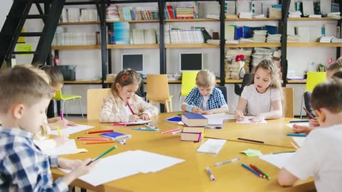 Children Drawing Together at Table in Library