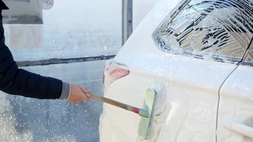 Man Washes White Vehicle at Car Wash