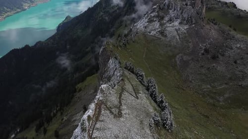Aerial shot flying forwards and tilting up along the dramatic, snow covered ridge of the mountain wi