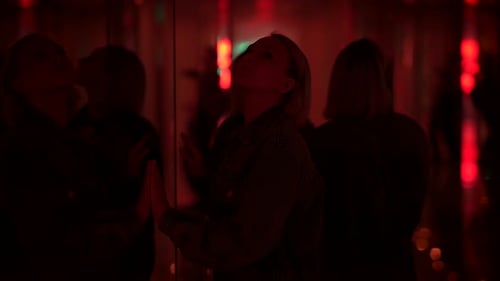 Young Blond Woman Exploring Room of Mirrors in Dreamlike Fantasy Neon Light