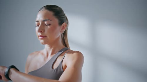 Athletic Woman Checks Fitness Tracker in Studio