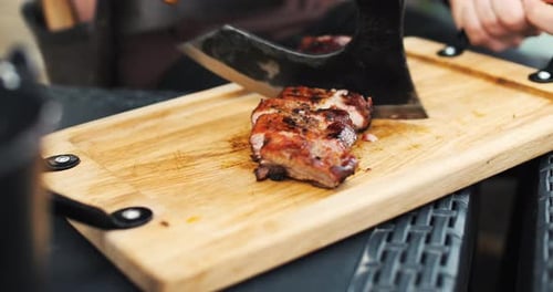 Le chef découpe des côtes grillées au barbecue avec un énorme couteau