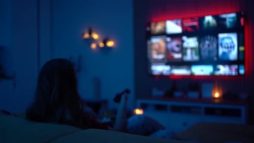 Child Relaxing on Sofa Watching Television at Night