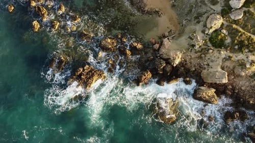 Sunset Drone Shot of sea waves hiting the rocks