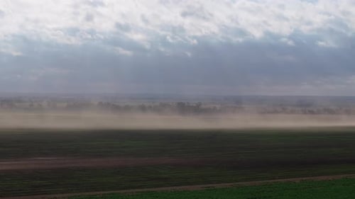 Dust storm sweeping across the highway with wind kicking up dust over open fields in Oklahoma
