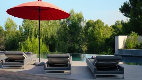 Slow orbiting shot of sun loungers and a umbrella at a villas private pool