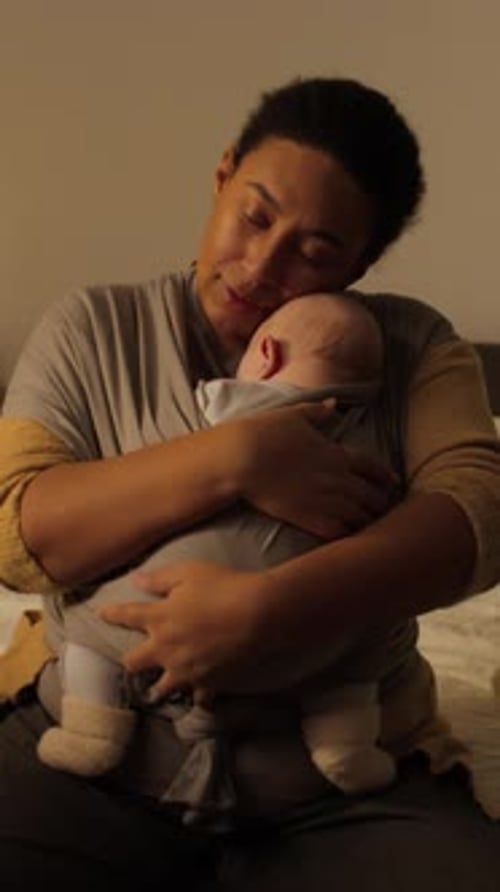Mother Holds Infant in Baby Carrier at Home