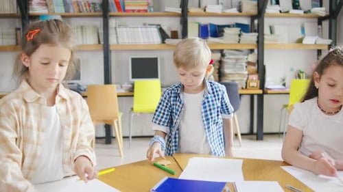 Elementary School Children are Fully Engaged in an Art Class Drawing and Coloring with Pencils and