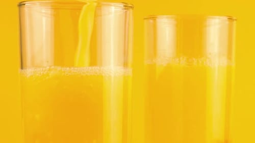 Orange Juice Being Poured into Glass with Ice