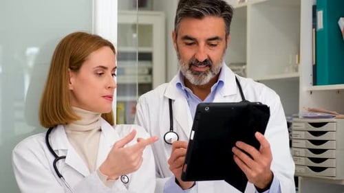 Doctors Reviewing Medical Information on Tablet in Office