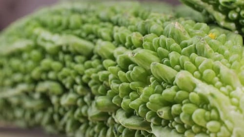 Une gourde amère, un légume souvent utilisé comme ingrédient en cuisine, est posée sur une table en bois.