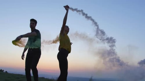 People Waving Smoke Grenades Outdoors at Sunset