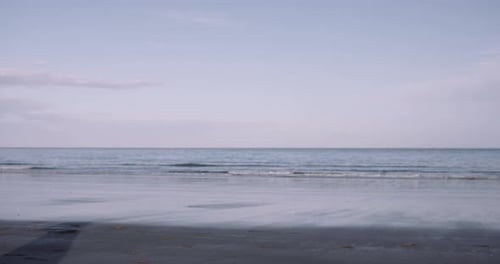 Young adult female dancing on beach by the sea
