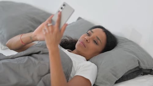 Woman Lies in Bed Using Smartphone
