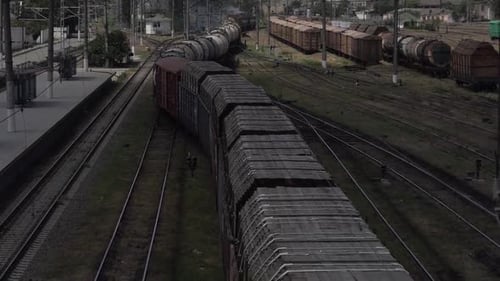 Trens ferroviários de carga se mudam para a estação de plataforma com vagões de óleo e madeira