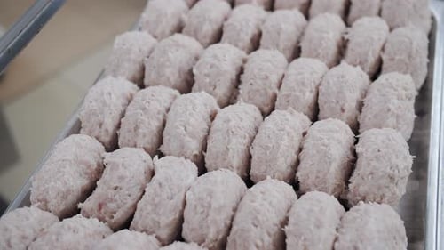 Rows of Pale Pink Sausage Meat on a Tray