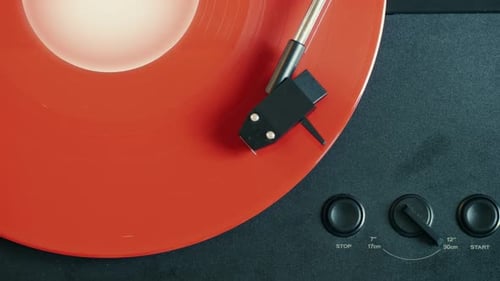 Orange Vinyl Record Spinning on Black Turntable