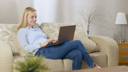 Woman Relaxing on Sofa Using Laptop at Home