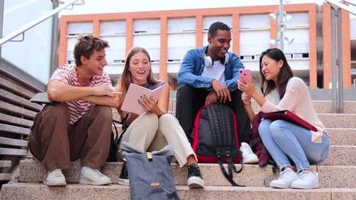 Group of Multiracial High School Students Talking on a Staircase at University Campus Using a Tablet
