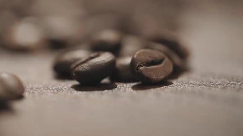 Close up and selective manual focus motion blur Scattering fresh coffee beans on a wooden table