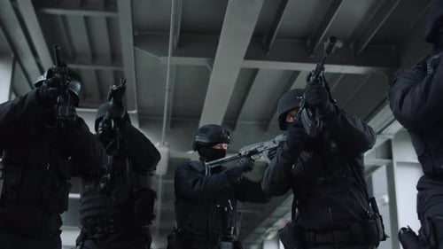 Swat team protecting urban building moving forwards along construction bridge