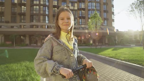 Girl with scooter stands in front of building