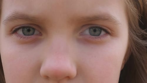Close Up Blue Eyes of Unhappy Little Blonde Girl Blinking and Looking Into Camera with a Despairing