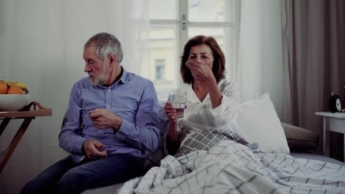 Senior Couple in Bed Takes Medication with Water