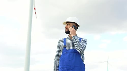 Wind Turbine Worker Next to a Wind Farm Talking on the Phone Clean Renewable Energy Technologies