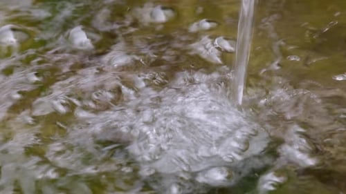 Bubbly water surface caused by a water stream falling.